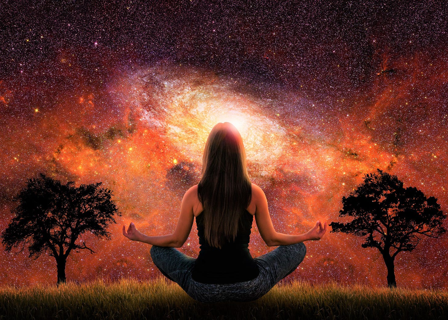 back view of girl with long dark hair in yoga pose looking at orange night sky