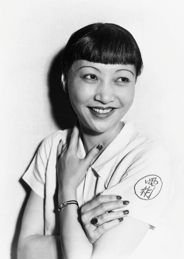 Black and white photo of Anna May Wong smiling in a white blouse
