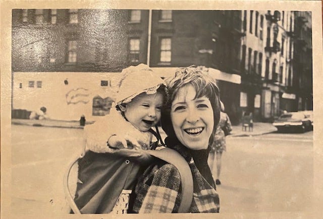 black and white photo of a laughing woman with short hair and a laughing baby on an NYC street