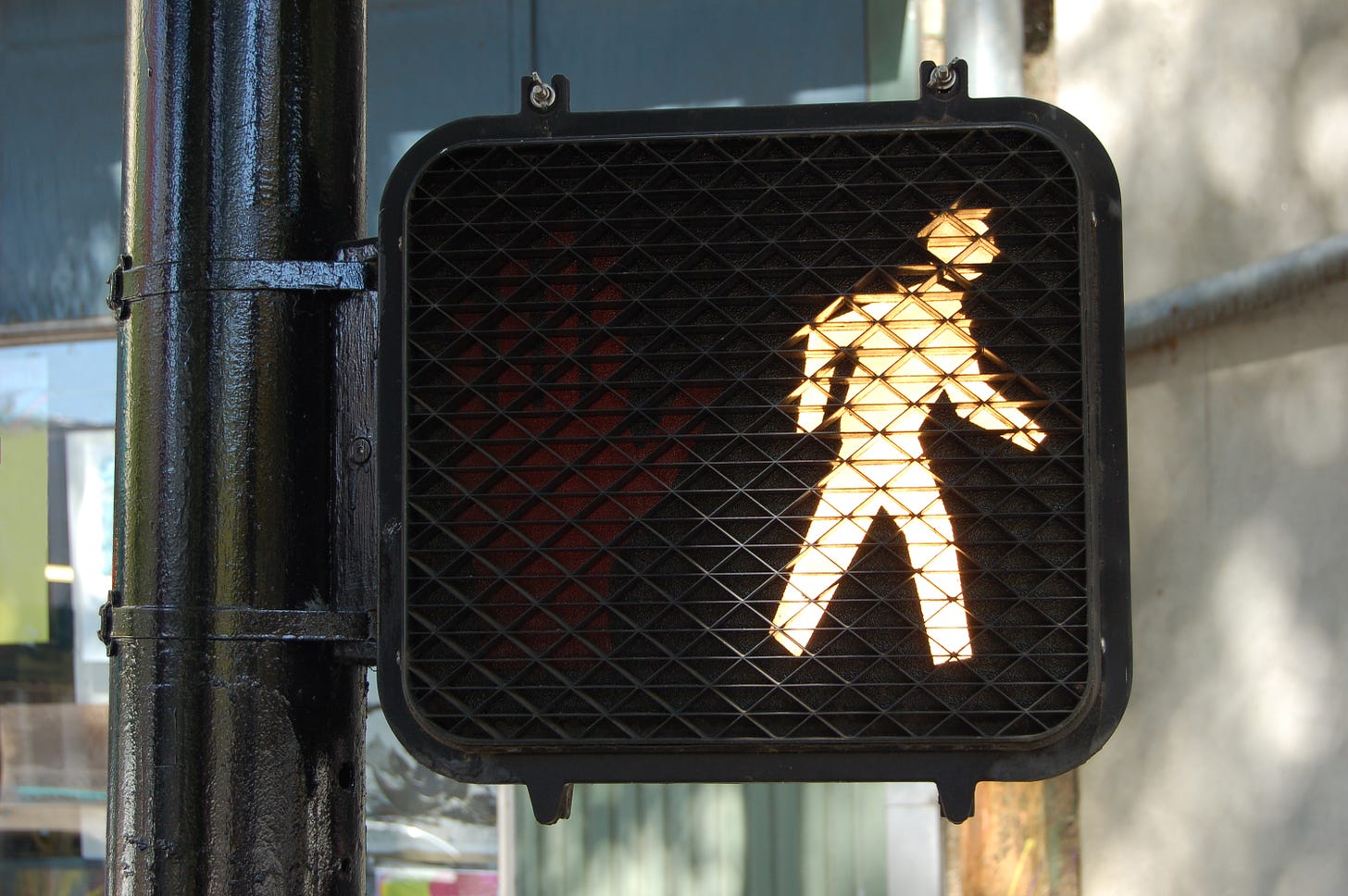 An activated pedestrian walk sign with illuminated person walking
