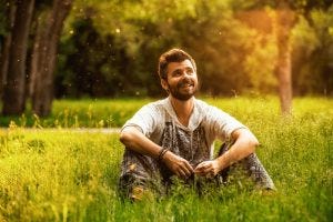© Maksim Petrov / 123RF.com - Happy cheerful man sitting on a grass at the park, smiling and lost in thoughts
