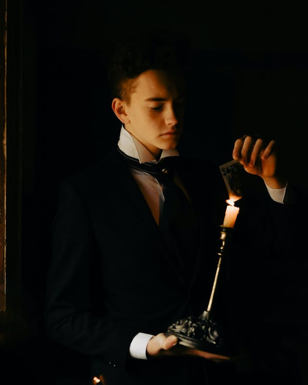 Magician Holding Candle Against Black Background