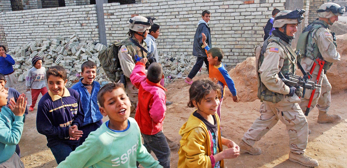 Three US Soldiers walk with children in the streets of Mamudiyah, Iraq, Dec. 30