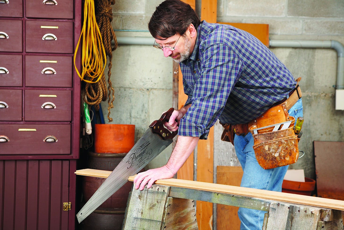 Norm Abram saws a board in his workshop