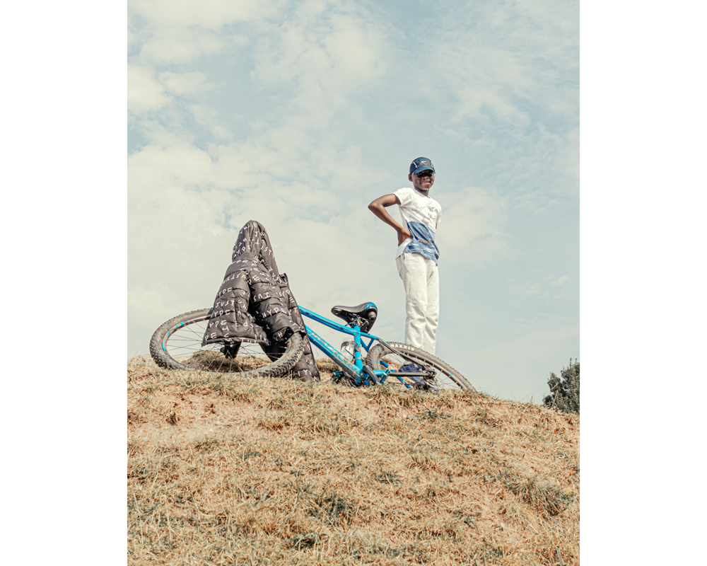 Boy with his bike on a small hill.png