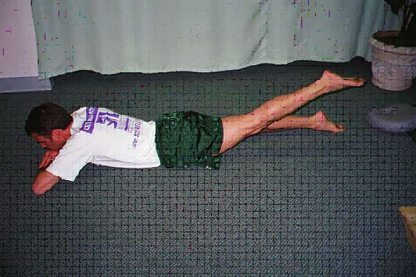A man lying prone on the floor with his left leg raised