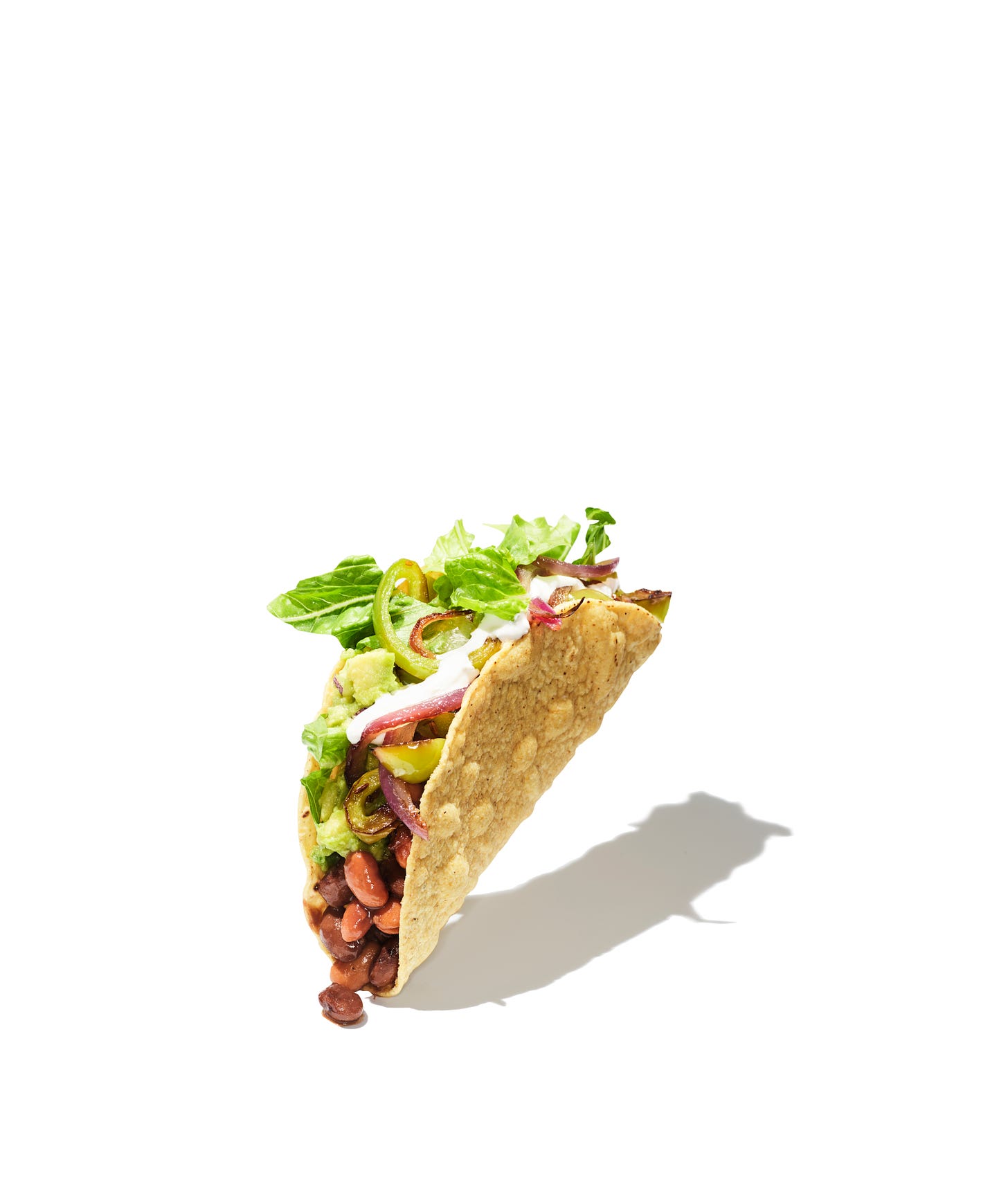 A bean and veggie puffy taco hovering on one corner,  obviously staged and stylized