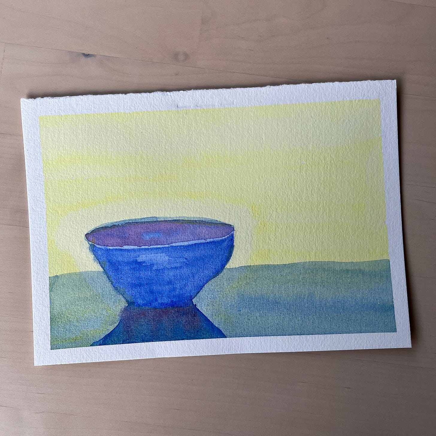 Image: a photo of my basic watercolour wash painting practice. A background of lemony yellow, with a china blue bowl on a bluish, greenish table.