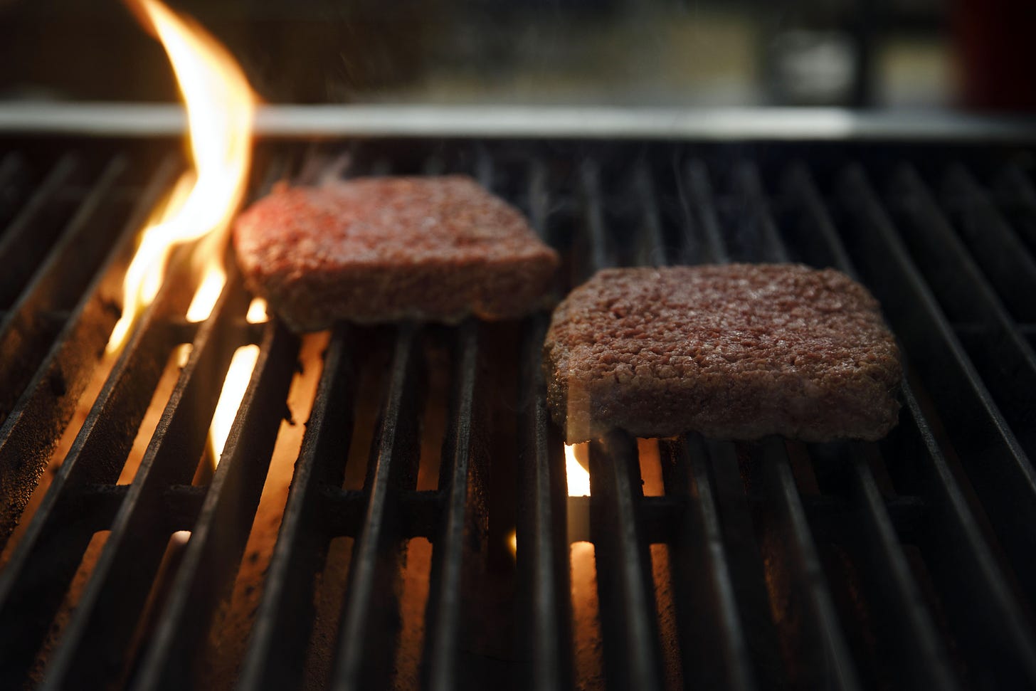 Two square burgers on an open flame grill