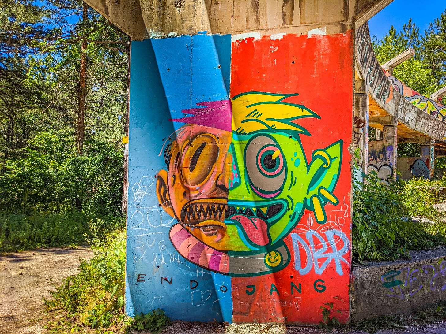 Graffiti painted part of the bobsleigh run. It shows a comical face with bug eyes, sharp teeth and tongue sticking out, all painted in bright colors. 
