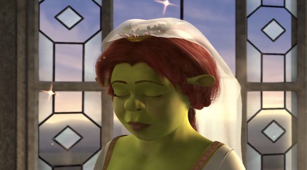 Fiona transforms into her true self in the wedding cathedral after being kissed by Shrek. Her true self is an ogre. She is backlit by the church window. Her eyes are closed as the last glimmer from the transformation sparks out around her. 