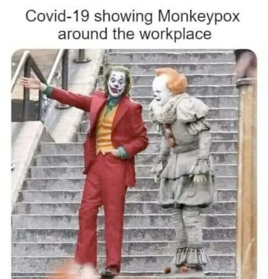  A photo of The Joker character standing on steps with another person dressed up as a clown, the Joker has his arm outstretched with open hand as if to gesture to the other clown. The caption above it reads Covid 19 showing Monkeypox around the workplace.