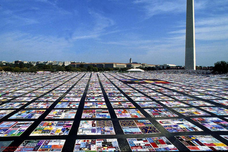 Blue sky above the horizon. Below it, a grid of colorful quilts stretches as far as he eye can see. The base of the Washington Monument obelisk can be seen at the far right of the photo.
