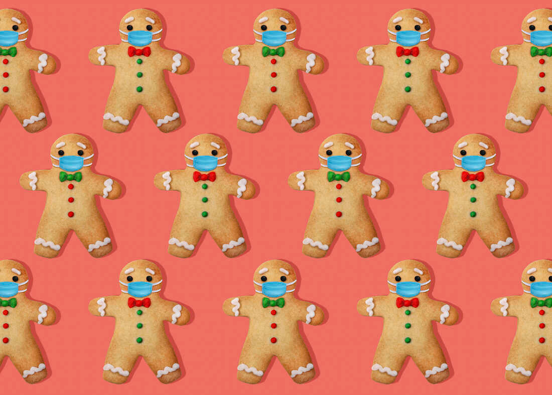 Gingerbread man cookies with surgical mask on pink background.