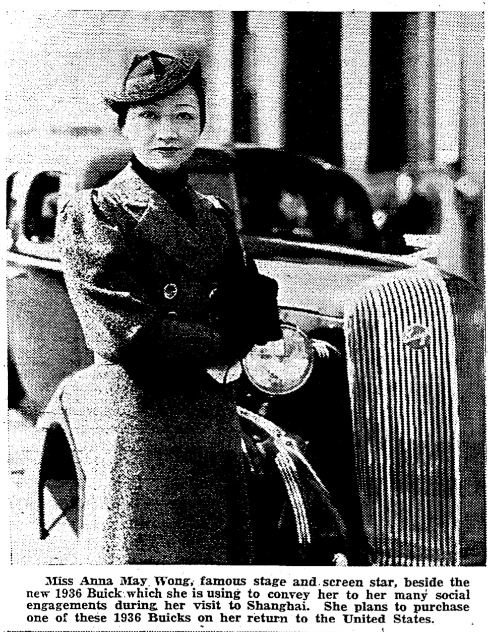 Anna May Wong, dressed in a coat and hat, stands in front of a 1936 Buick in Shanghai