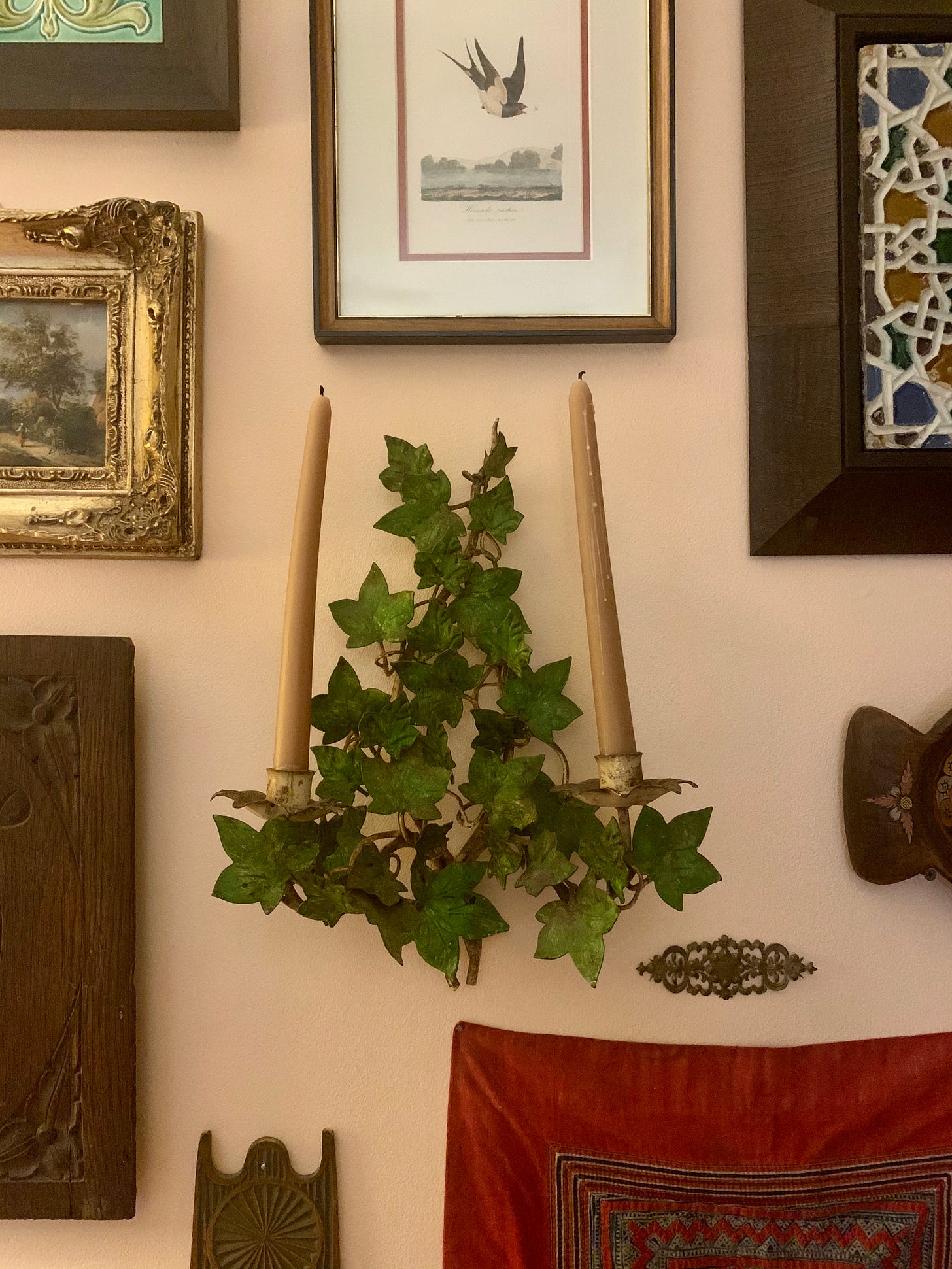 Two candles on a toleware sconce with ivy leaves