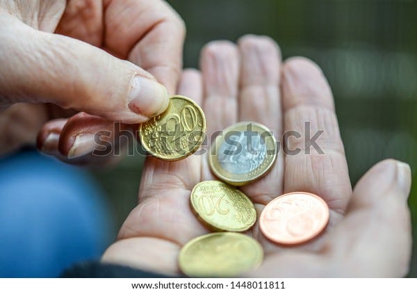 Poids de l'image: Une femme pauvre et exubérante tient des pièces d'Euro et de Cent dans sa main - gros plan avec une mise au point sélective avec très peu de profondeur de champ 
