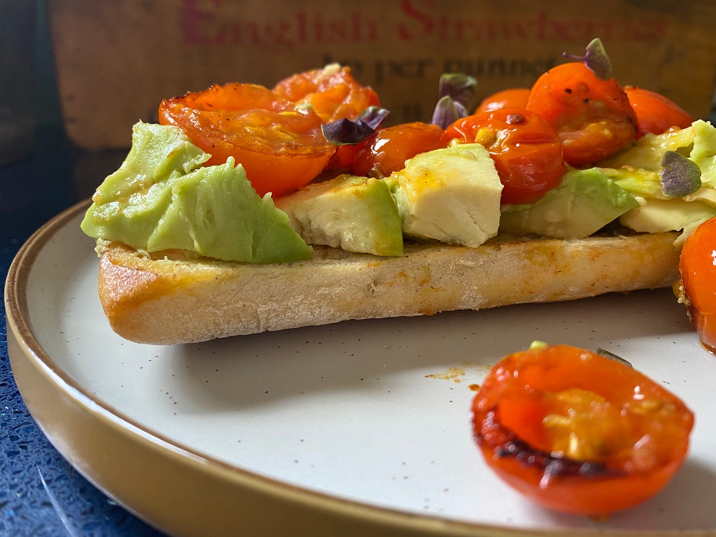 Piece of toasted bread with chopped avocado and cooked, halved tomatoes