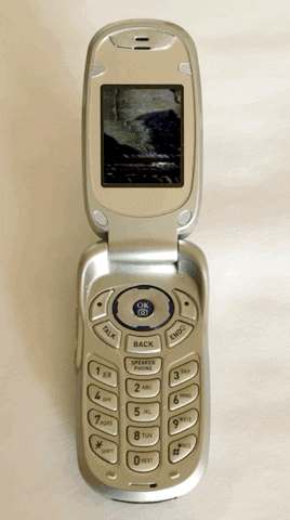 um celular antigo de flip, cinza metálico, passando um video indistinguível
