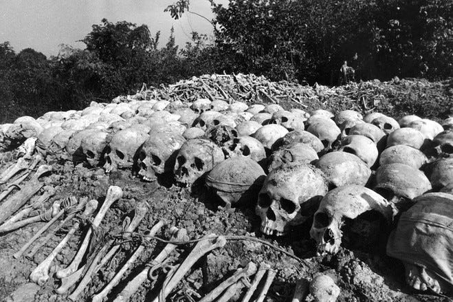 An endless line of freshly exhumed skulls, lined up six deep, eat dirt as they face the camera, and in the background a giant pile of bones.