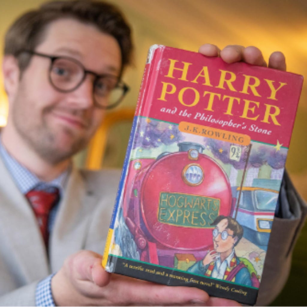 A man holds a first edition Harry Potter book.