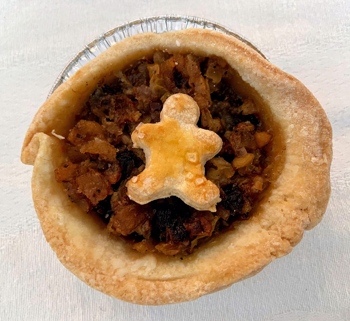 A mince pie with a pastry man on top