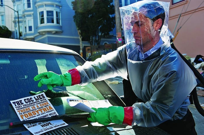 Jude Law, in full PAPR gear, removes a conspiracy theory propaganda flyer in the 2011 film Contagion.