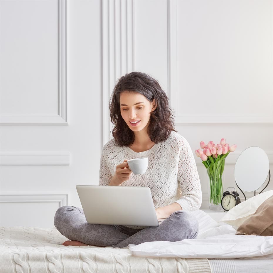 Woman with a cup of coffee making friends with the blank page on her laptop before she starts writing.