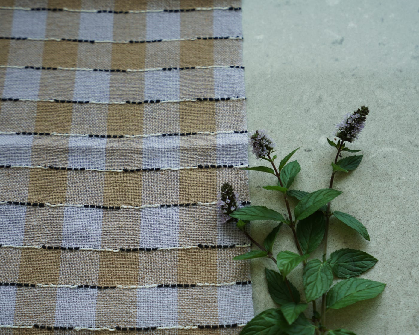 A flat cloth on a countertop with three flowering sprigs of mint