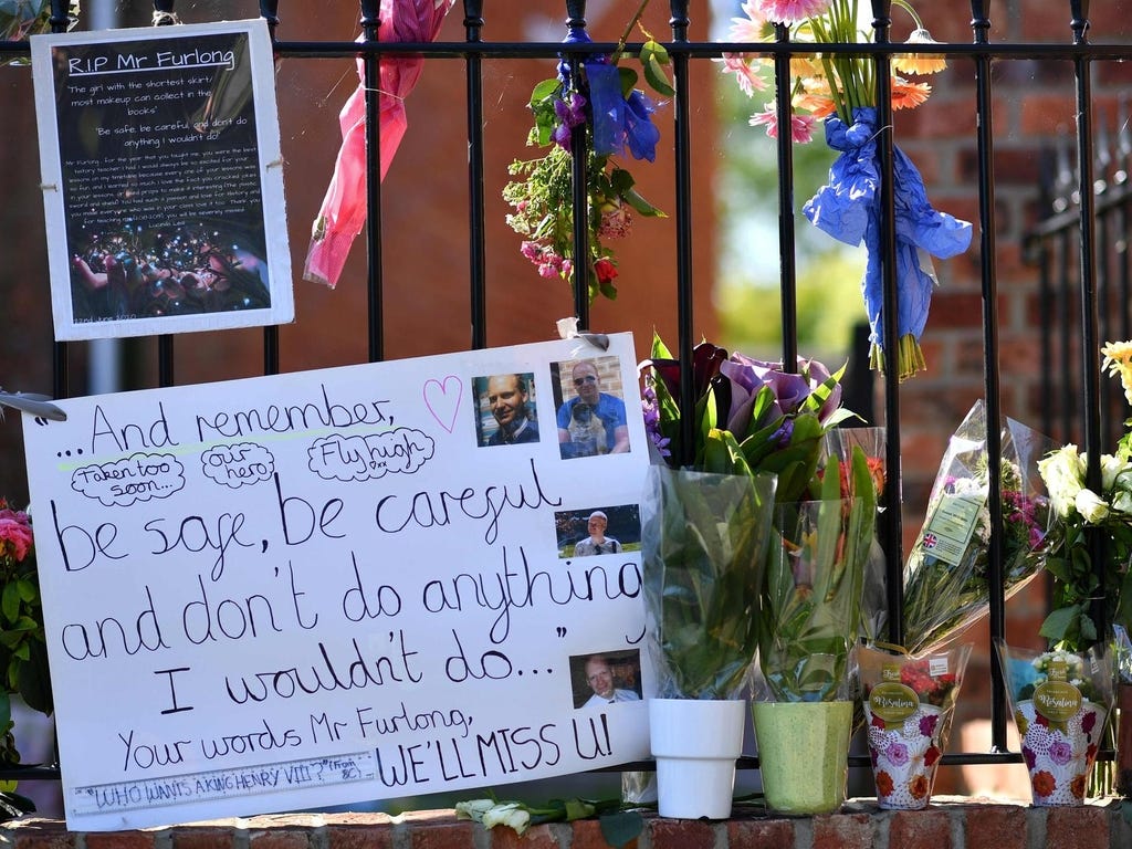 Floral tributes are left on the railings outside The Holt School in Wokingham on June 23, 2020 in memory of teacher James Furlong who was a victim in the knife attack in Reading which killed three people. UK counter-terrorism police have been given until June 27 to continue questioning the suspect in the Reading park attack which saw three people stabbed to death, officers said. / AFP / Ben STANSALL