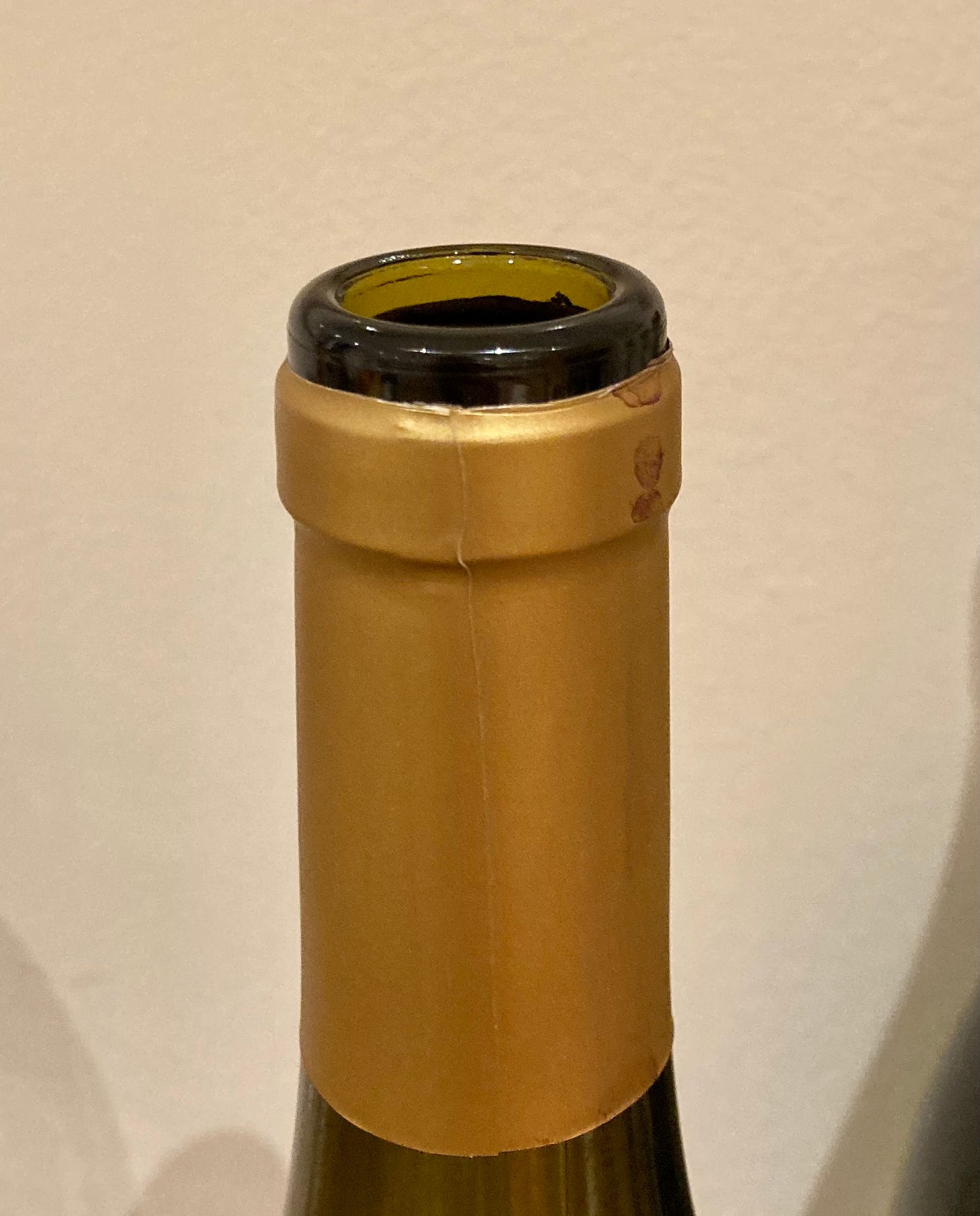 A wine bottle with a capsule that has had the top removed to give access to the cork.