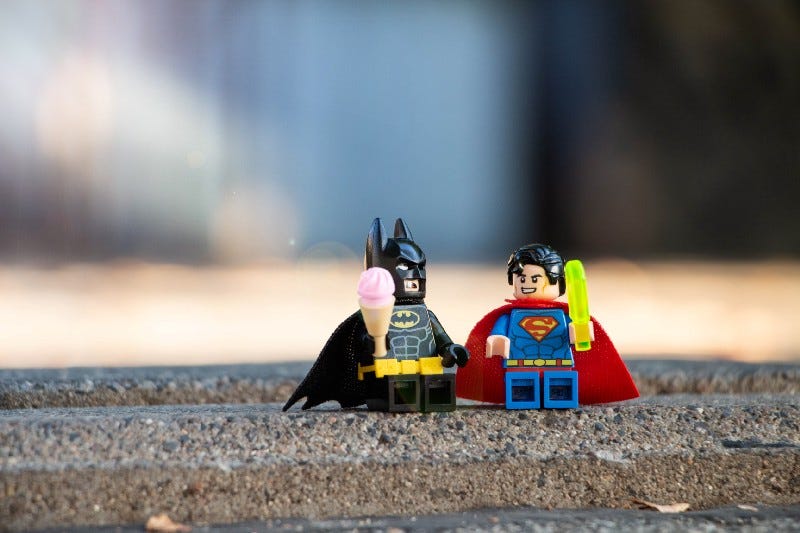 Lego figures of Batman and Superman, eating ice creams.