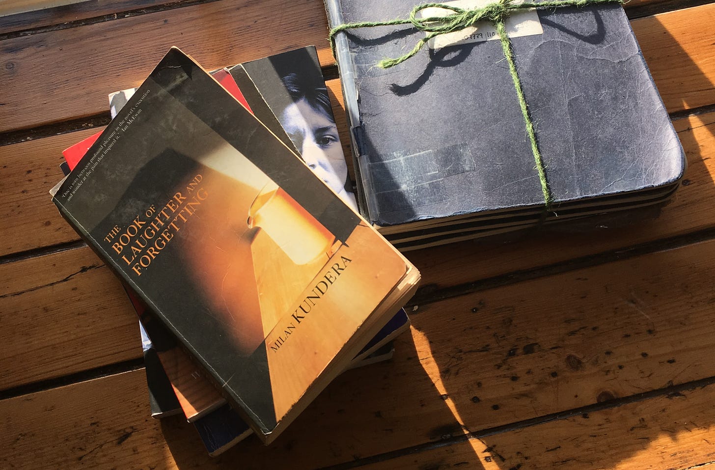 A copy of The Book of Laughter and Forgetting by Milan Kundera on a windowsill, with golden light falling across it