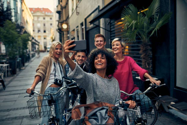 Friends Riding Bicycles In A City Friends Riding Bicycles In A City. Cycling in pedestrian zone and making selfie. Group travel stock pictures, royalty-free photos & images
