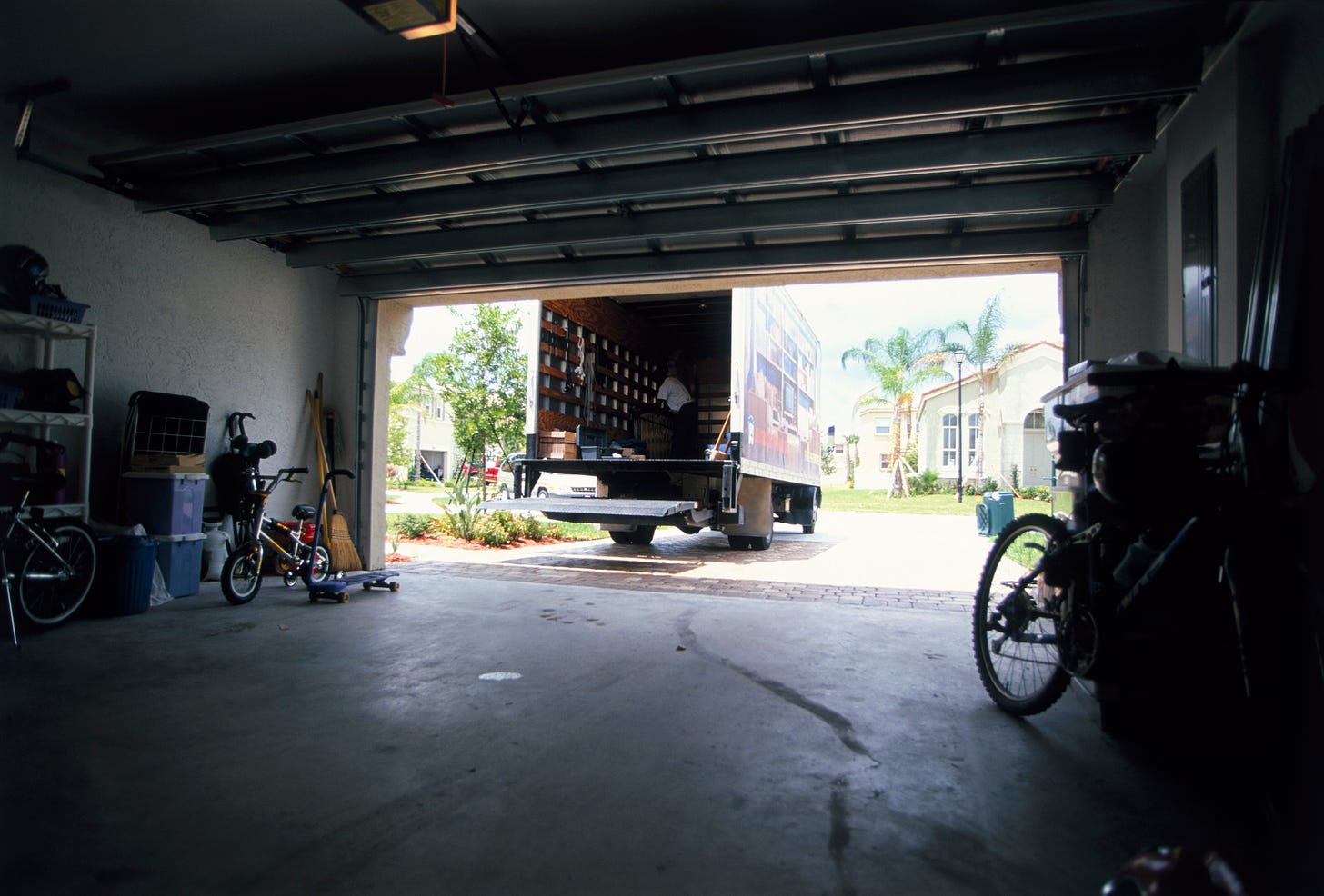 Suburban garage with bikes and skateboards with a moving truck parked in front