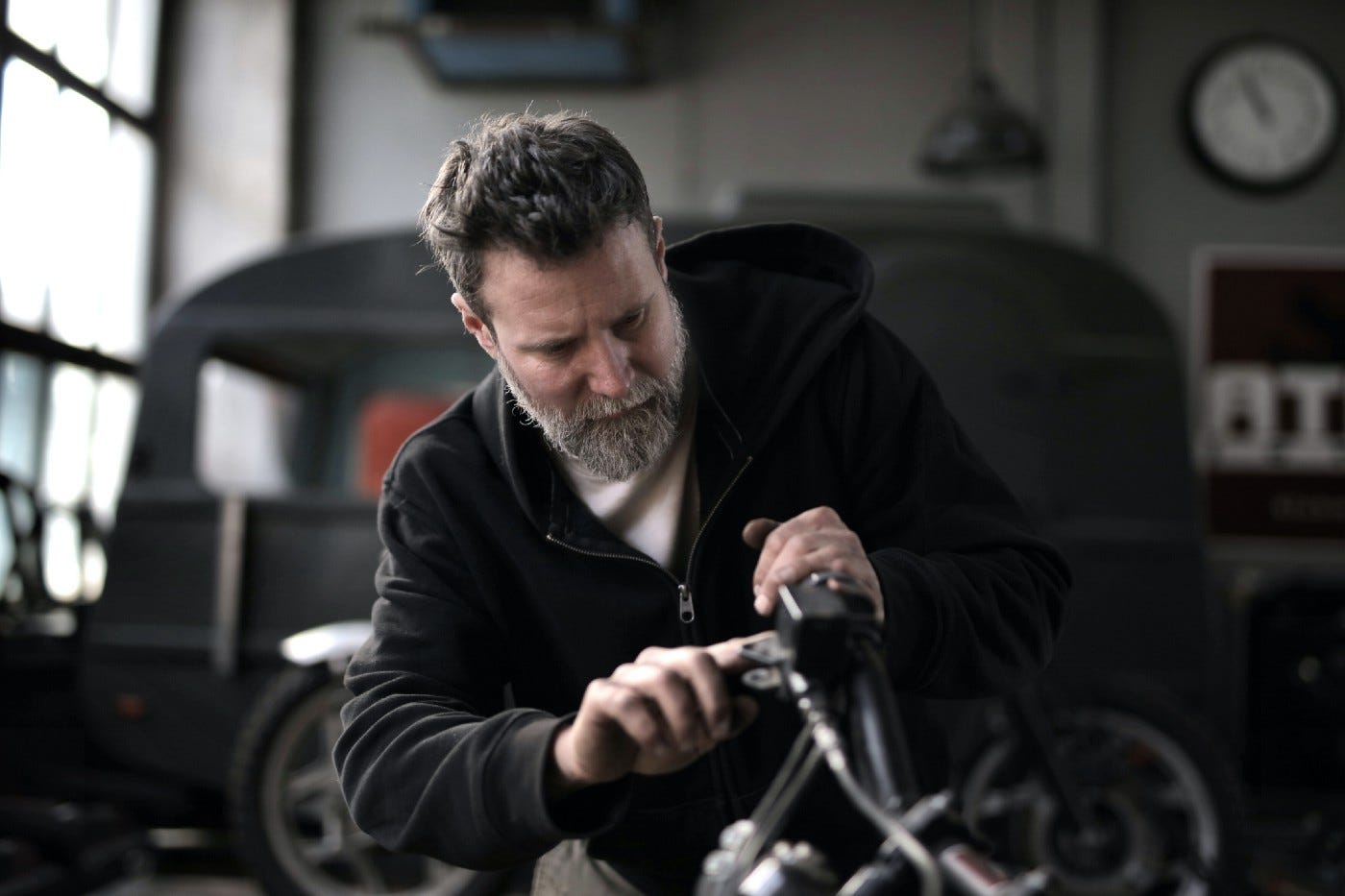 Bearded old man attending to a bike in a fancy garage