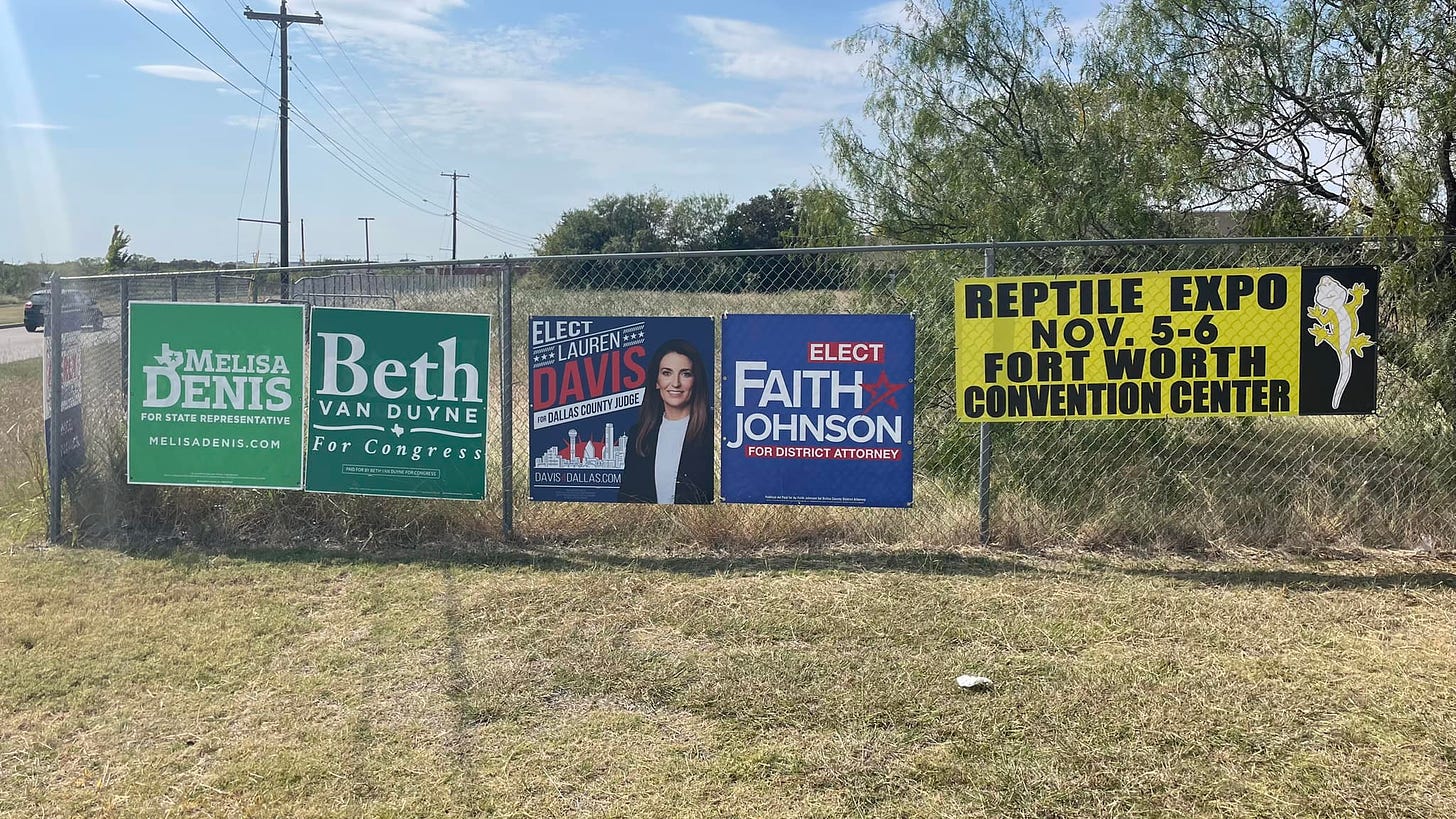 Four campaign signs next to a sign touting a Reptile Expo