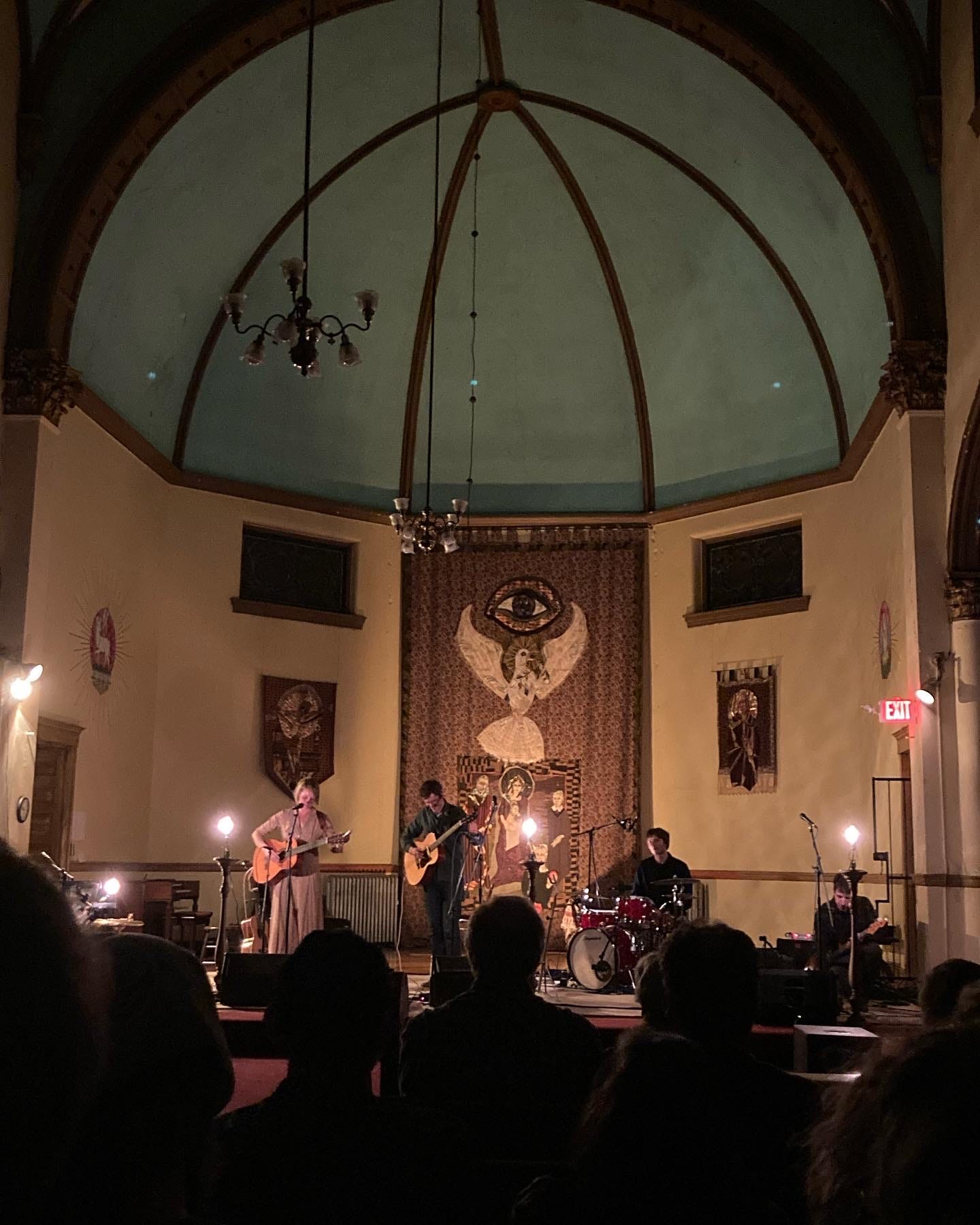 Stage in a church lit up in the dark with Joan Shelley and her band playing