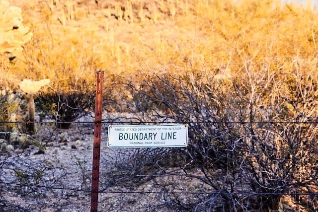 fence in a field with “boundary line” sign on it