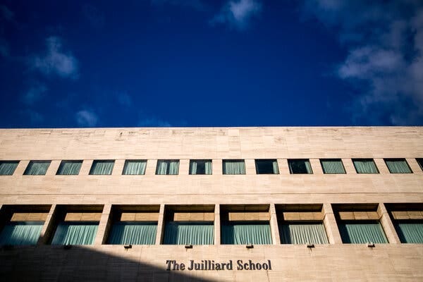 The words “The Juilliard School” on the facade of a building with many square windows covered by curtains.