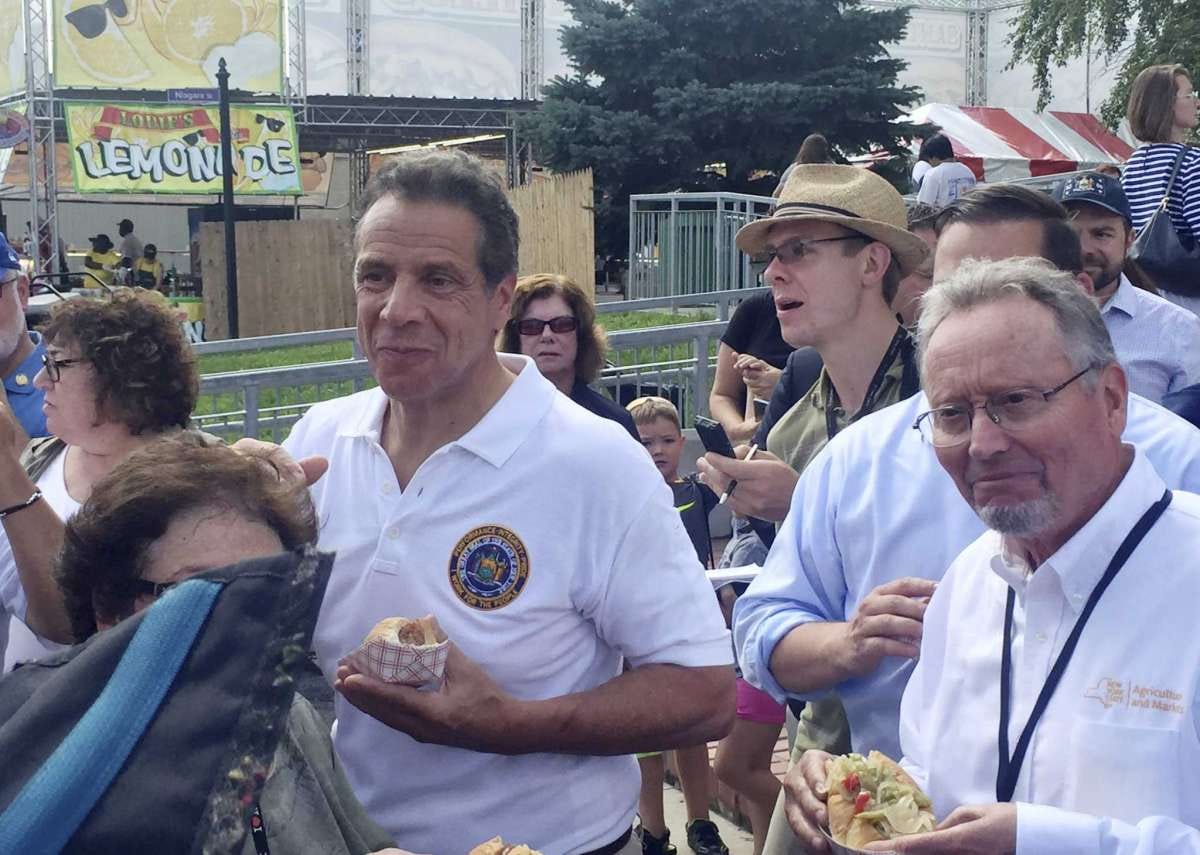 Richard Ball, right, commissioner for the New York state Department of Agriculture and Markets, right, joins New York Gov. Andrew Cuomo at the New York state fair, Wednesday, Aug. 21, 2019 in Syracuse, N.Y. Ball announced on Wednesday that the state fair will be solely powered by renewable energy by 2023.