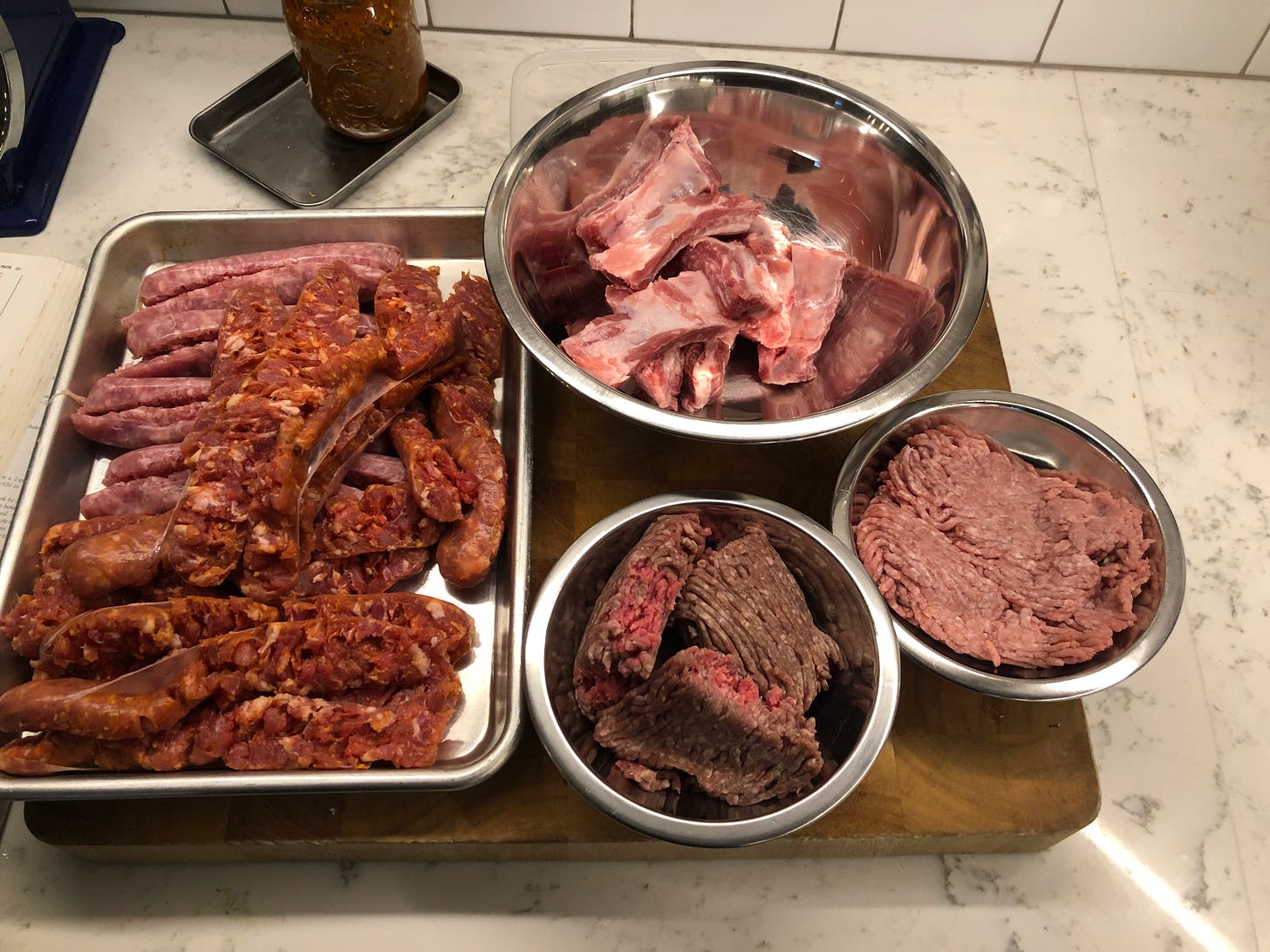 An arrangement of  sausages, ribs, ground beef, and ground pork