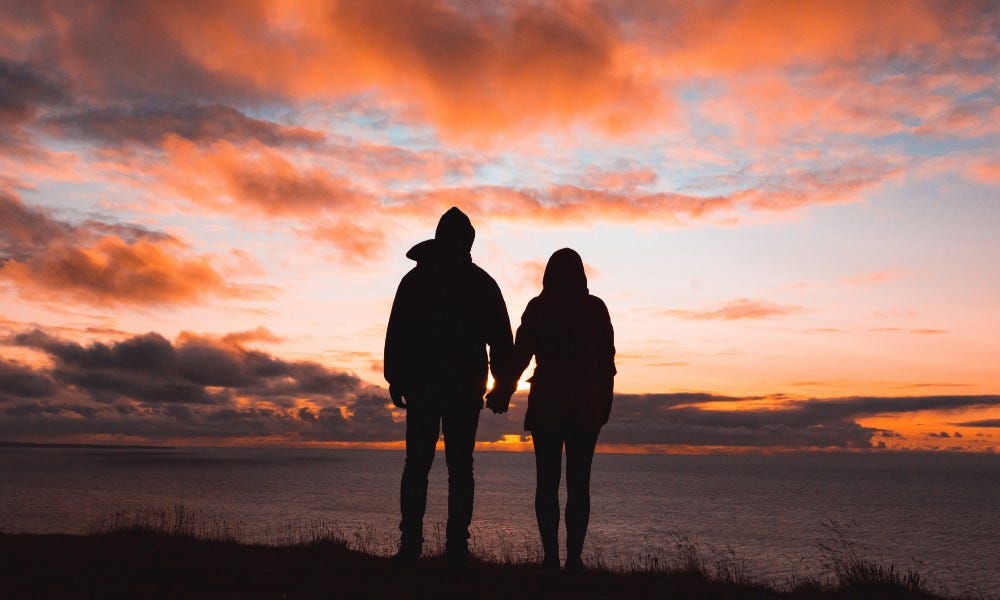 man and woman holding hands in silhouette