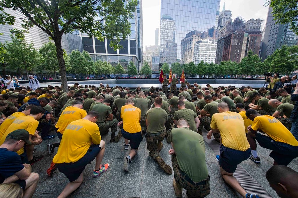 Marines and Sailors kneel during a moment of silence at the National September 11 Memorial & Museum.