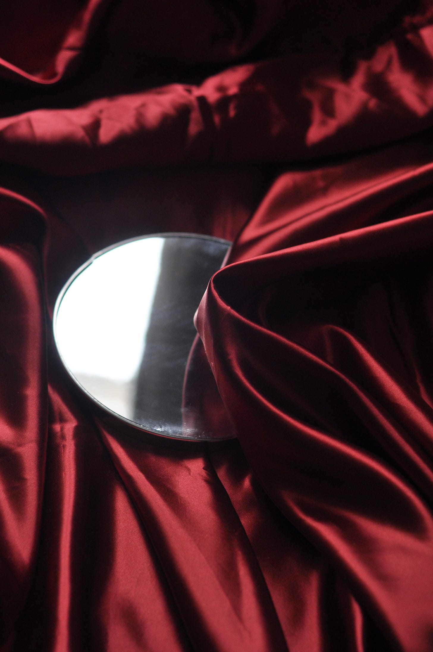 Dark red silk folded over a round mirror.