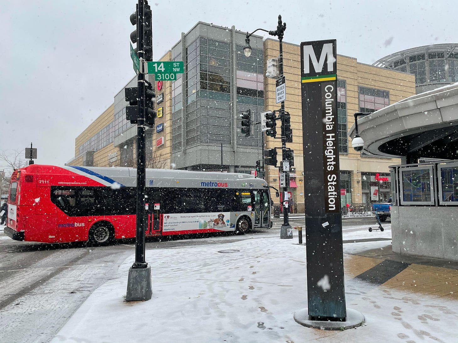 Metrobus travelling north along 14th Street NW passing Columbia Heights Metro Station in the snow