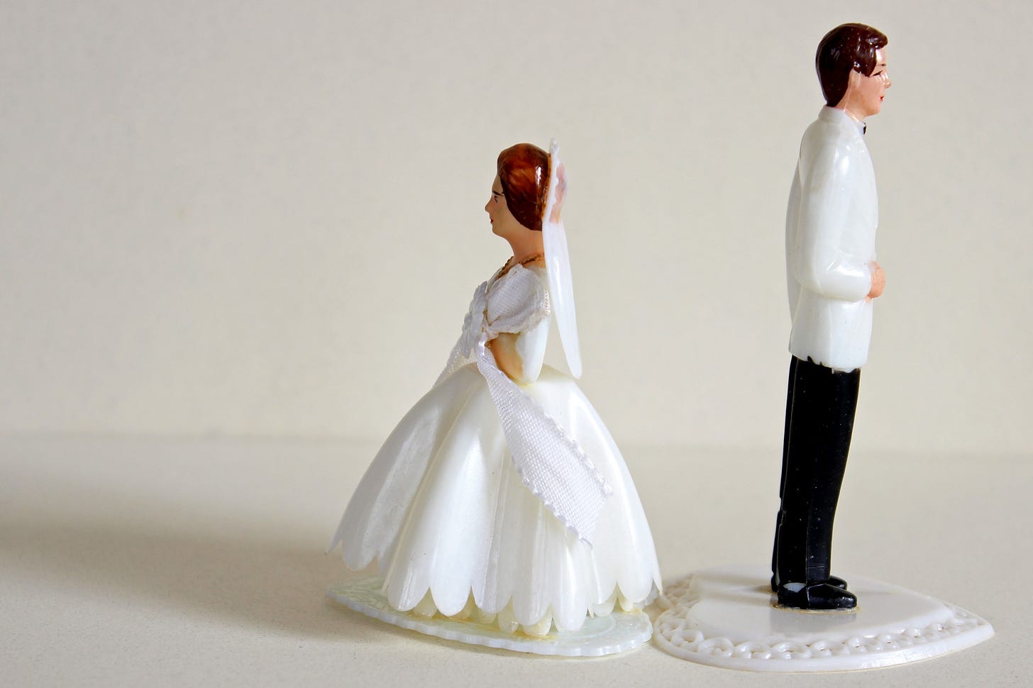 A man and woman wedding topper face away from one another.