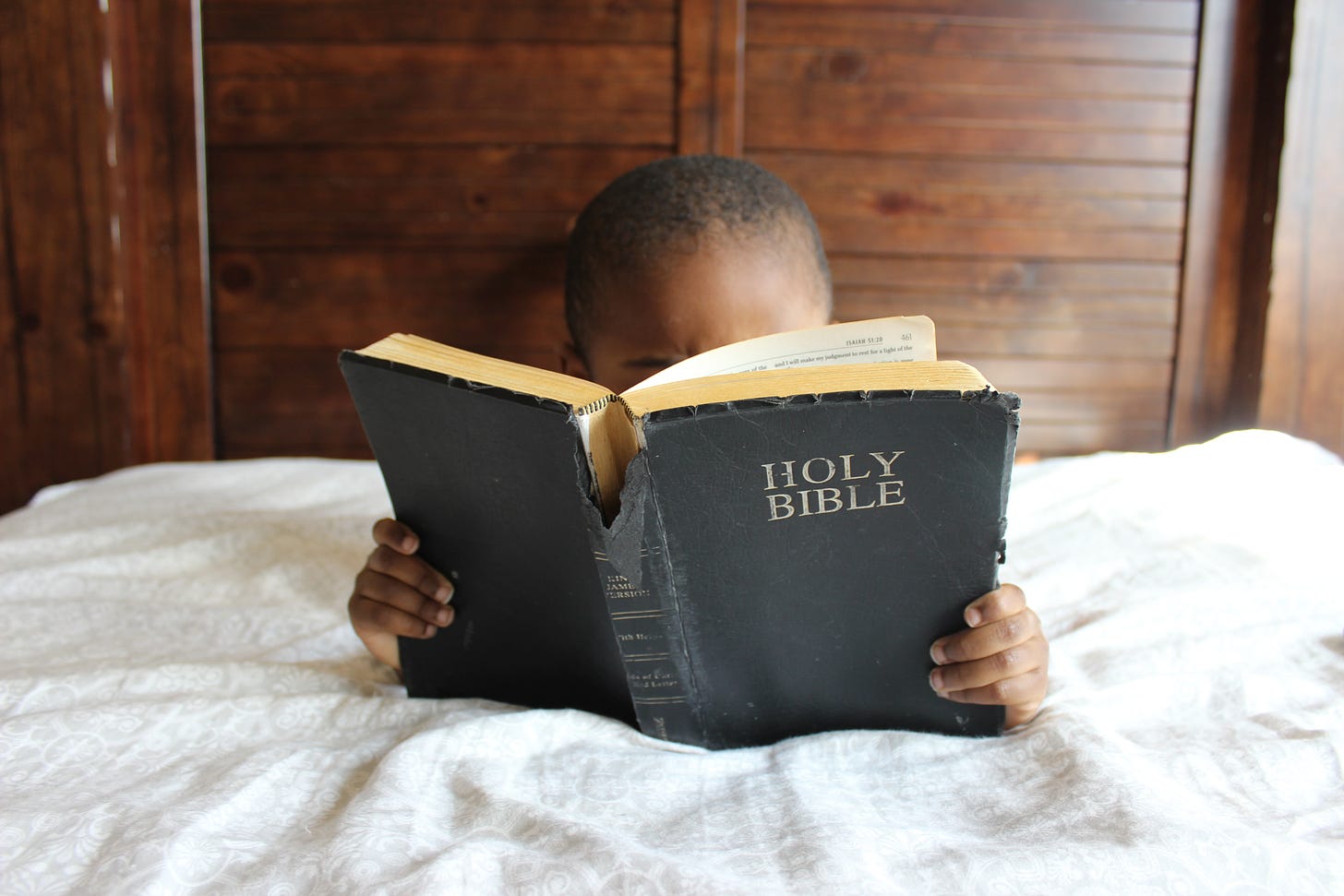 Image of a child reading a tattered Holy Bible, free from Upsplash