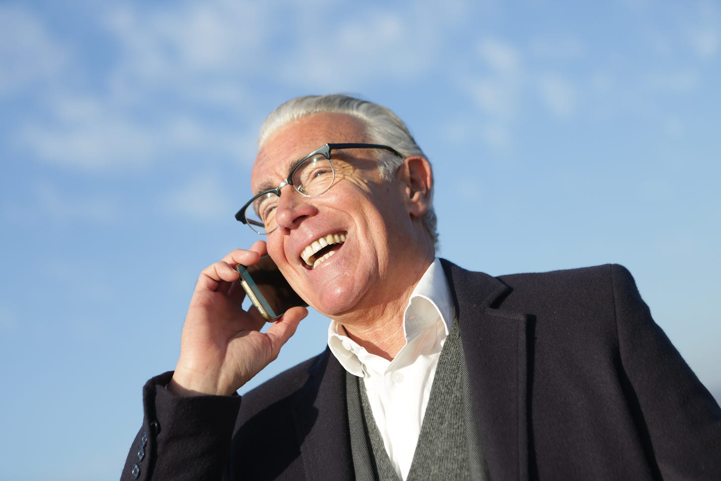 A smiling older man talking on his cell phone.