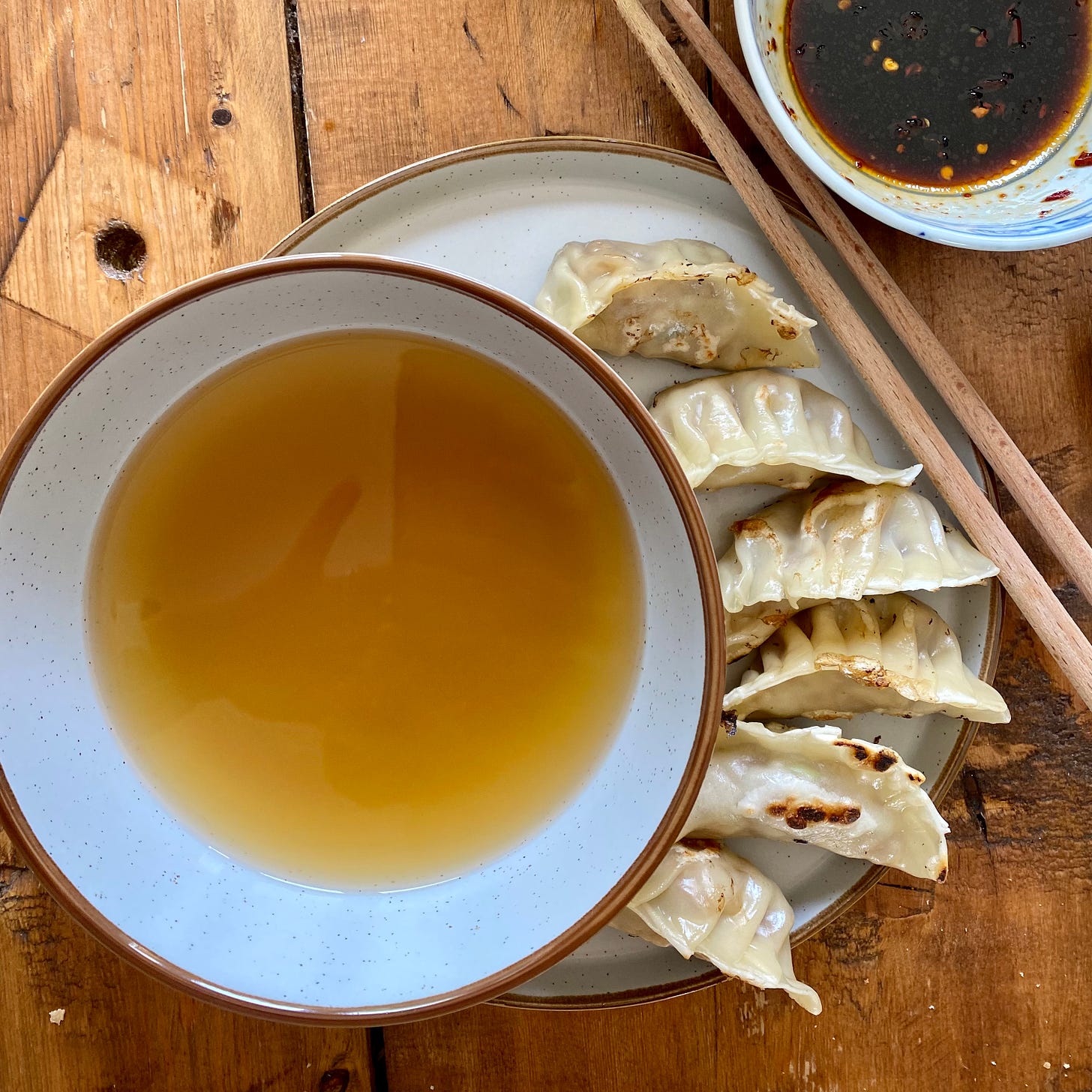 Bowl of miso soup, with six gyoza alongside and a small bowl of dipping sauce and chopsticks